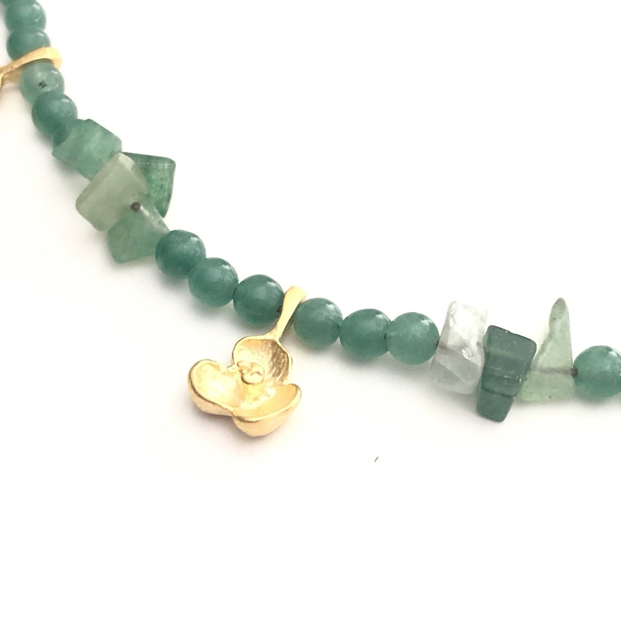 Elegante collar corto de piedra agata y cristal facetado verde, con unas flores de Zamak con baño de oro mate. Esta pieza contiene un cierre filigrana con baño de oro. Este collar es ideal para combinar con tus prendas favoritas. Detalle flor