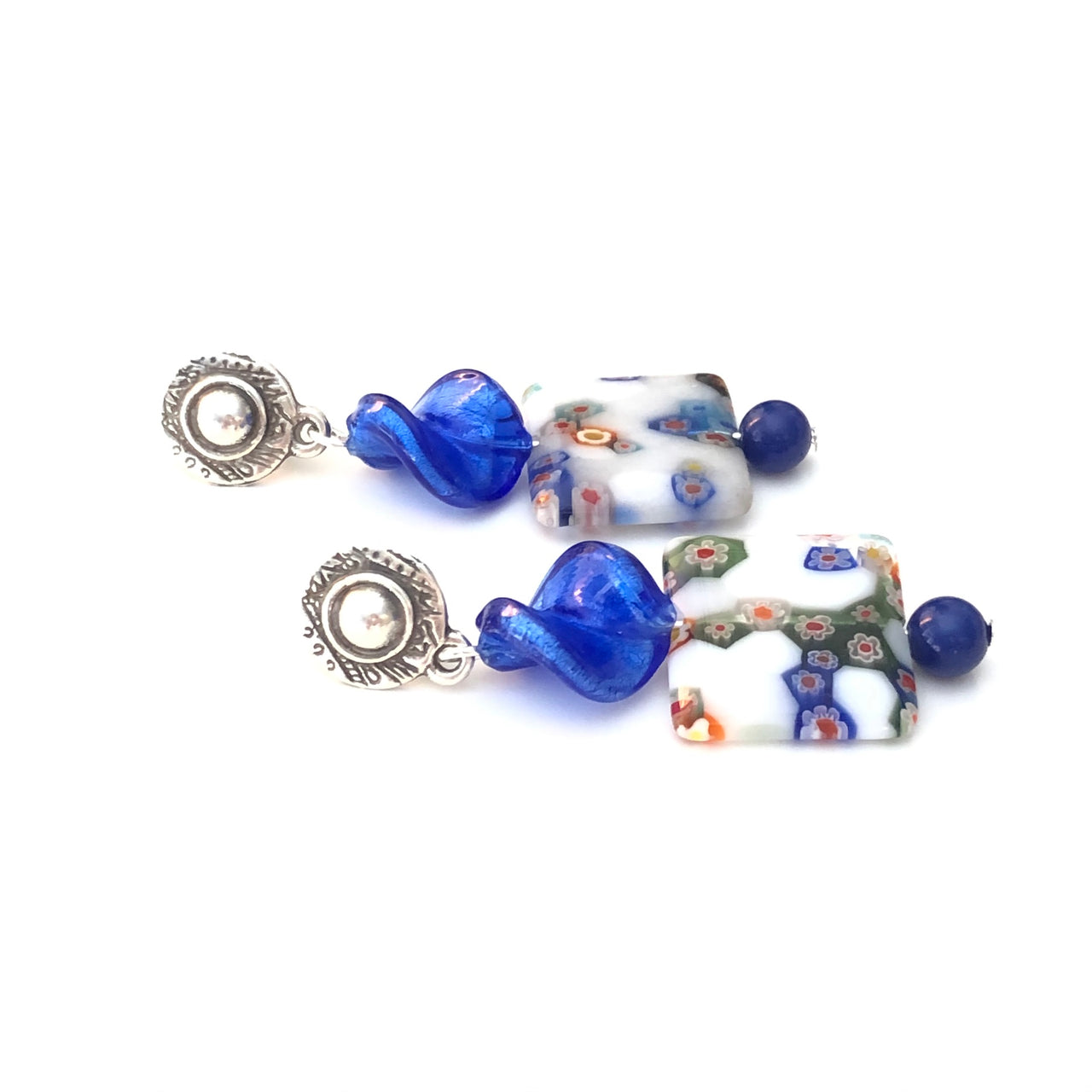 Pendientes martillados de Zamak con baño de plata, con un twist de cristal azul y unos cristales cuadrados blancos y azules y una cuenta de ágata azul, hacen de esta pieza una obra de arte. Estos pendientes son simplemente ideales para cualquier estilo. Combínalo como quieras. Horizontal